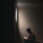 A picture of a guy reading in a dark room.