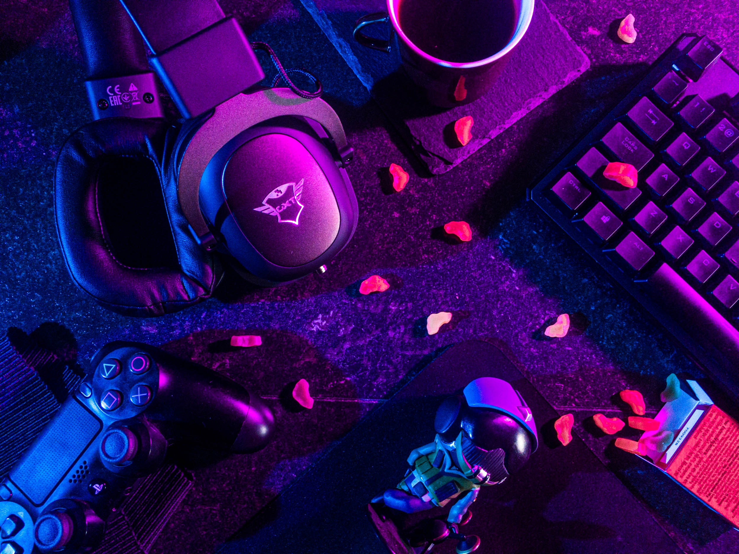 A picture of several pc peripherals laying on a table in a purple glow.